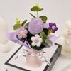 A handmade crochet tulip bouquet featuring purple and white flowers in a pink paper wrapping.