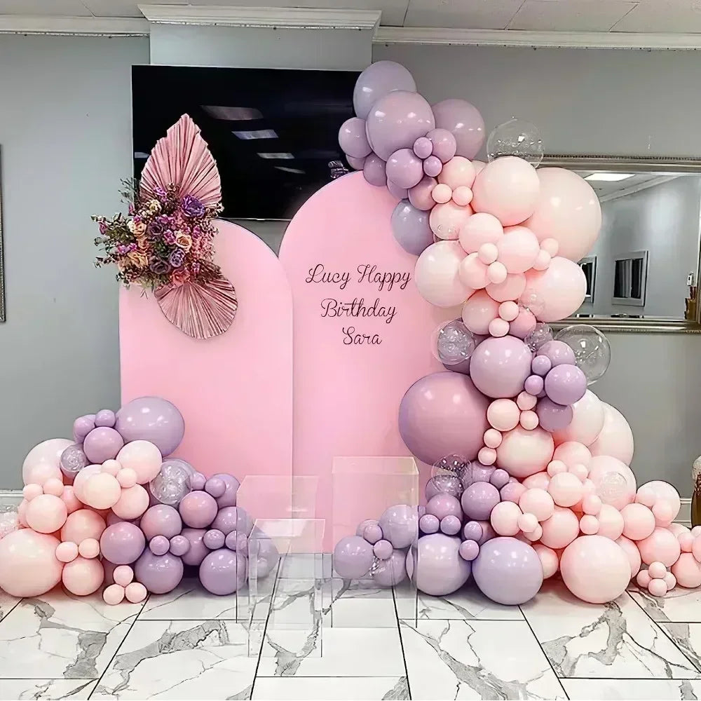 Fondo de arco de globos rosa y morado con globos grandes y un letrero personalizado para un evento de cumpleaños.