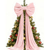 A festive Christmas tree decorated with gold and red ornaments and a large pink velvet bow with long draping tails.