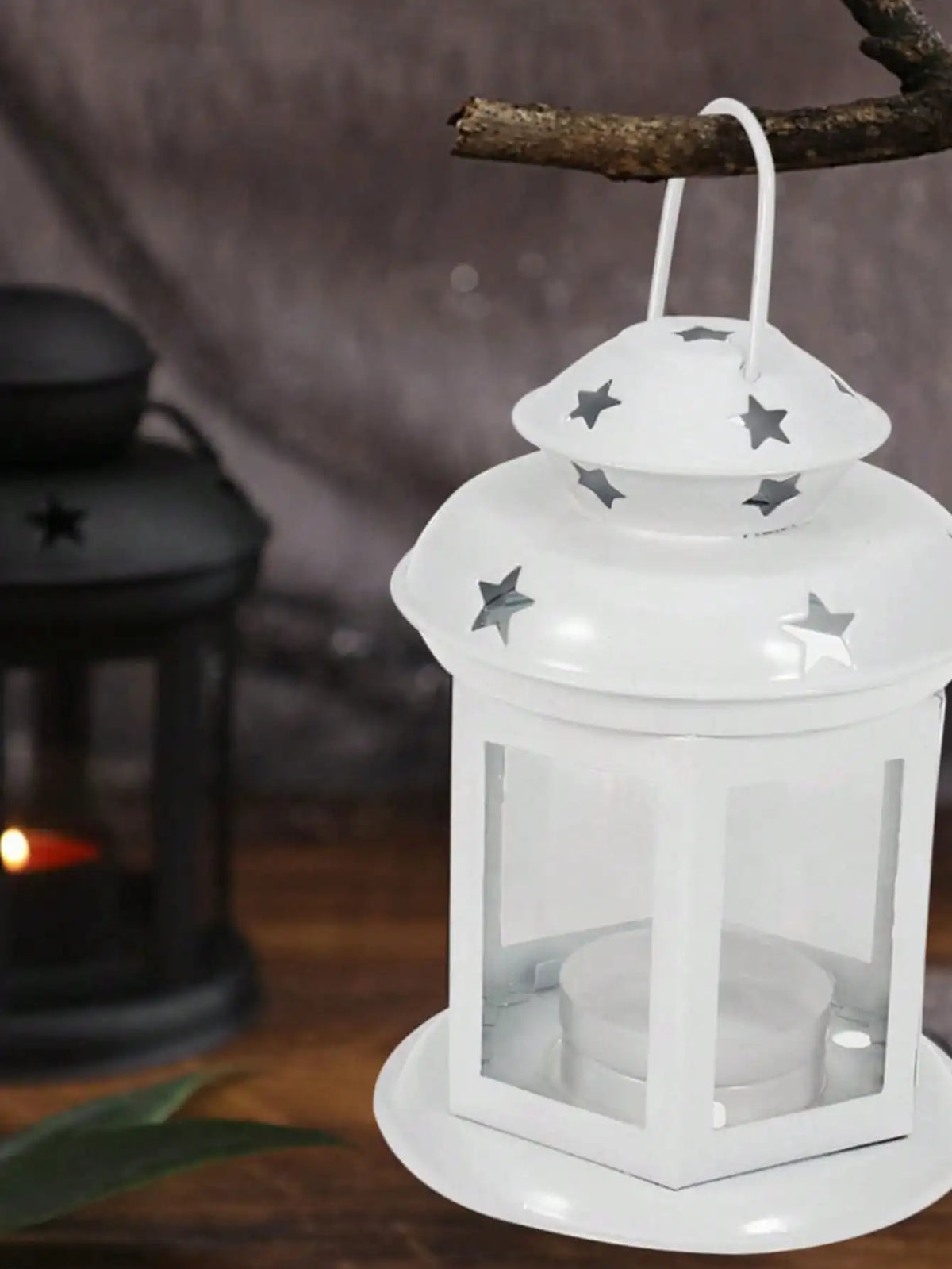 A white vintage hanging metal lantern with a glass enclosure and star accents is displayed against a dark background.