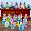 A collection of miniature resin magic potion bottles in various colors and shapes displayed on a wooden surface.