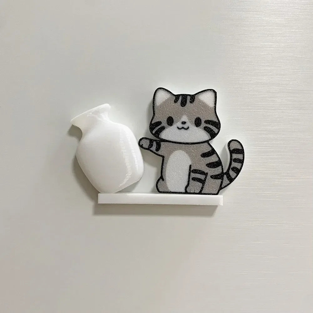 A small, gray and black cat face decoration made of acrylic is mounted on a white magnetic strip.