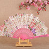 Pink and purple silk flower folding fan with intricate patterns displayed on a wooden stand.