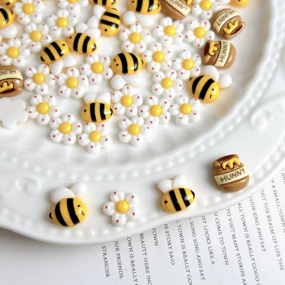 A white plate covered with small yellow and black bee and daisy resin charms.