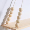 A pair of natural wooden beads hanging on a white string against a light background.