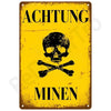 Vintage yellow metal sign with black text warning about mines featuring a skull and crossbones symbol.