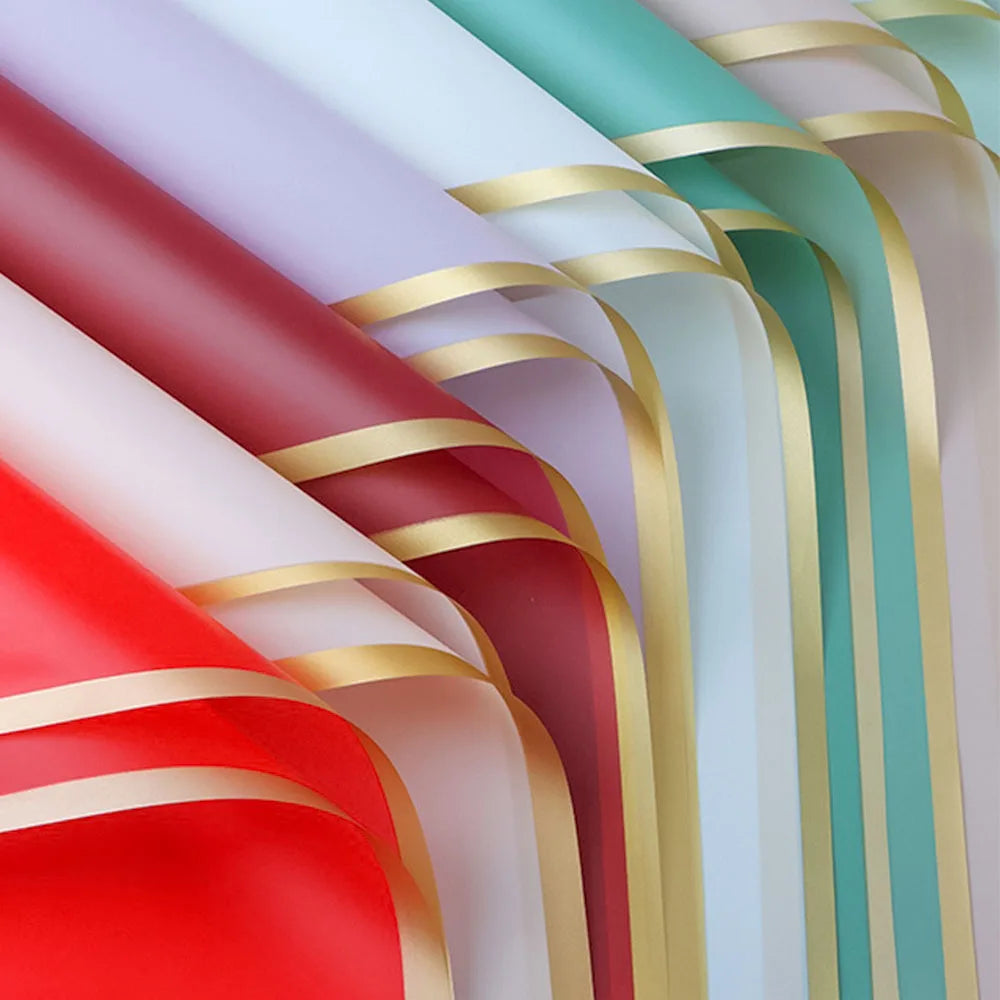 Vertical display of gold and colored wrapping paper rolls, showing various shades of red, green, and pink.