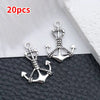 A pair of silver vintage ship anchor charms for jewelry making displayed on a black surface.