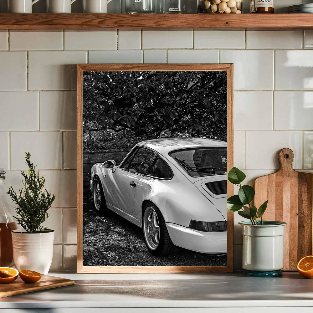 Photo encadrée noir et blanc d'une voiture de sport blanche garée à l'extérieur sur une surface pavée.