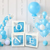 A white box containing blue balloons with the letter O N E for first birthday and baby shower decorations