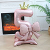 A large pink foil balloon shaped like the number 5 with a gold crown on top