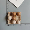 A set of six brown and white egg-shaped food magnets arranged on a measuring ruler.