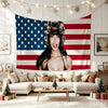 A woman wearing a patriotic helmet poses in front of a pink USA flag tapestry hanging on a white wall.