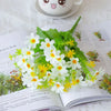 A close-up of white and yellow artificial daisy flowers arranged on an open book page.