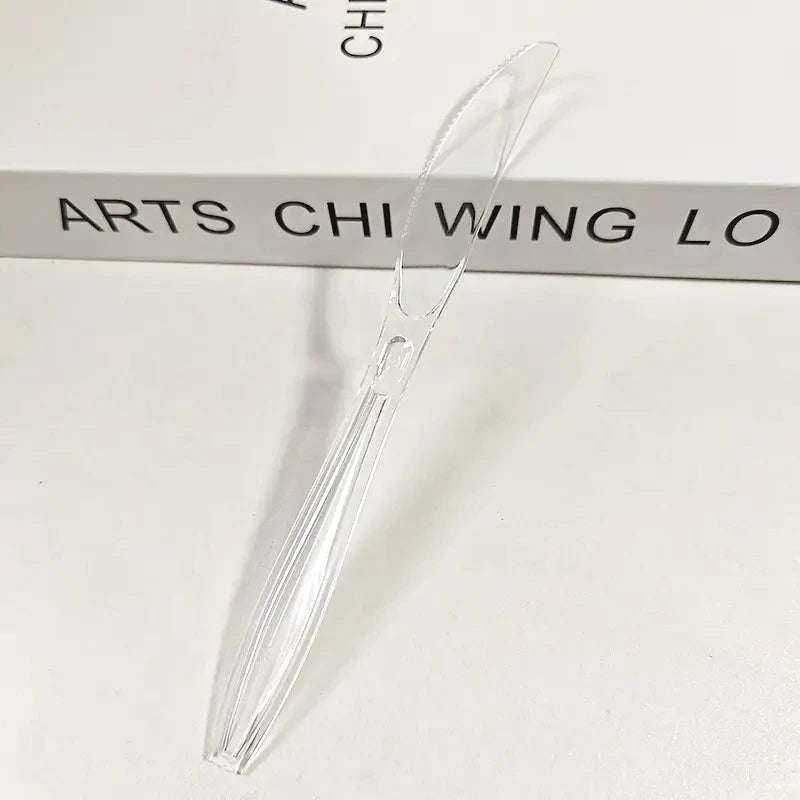 A clear plastic cutlery set with a tapered design is shown resting on a white surface.
