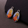 Une paire de pendentifs argentés représentant des figures religieuses, dont la Miséricorde Divine et Saint Michel, exposés su