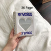 A white photo album titled My World with a heart cutout and the text My Space is held in a hand on a white bed.