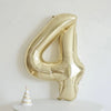 A large champagne gold foil number balloon shaped like the number four displayed on a white surface.