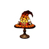 A decorative night light shaped like a witch hat with a stained glass effect featuring skulls and orange hues.