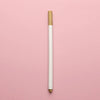 A vertical view of a transparent wax sealing bead with a gold cap against a pink background.