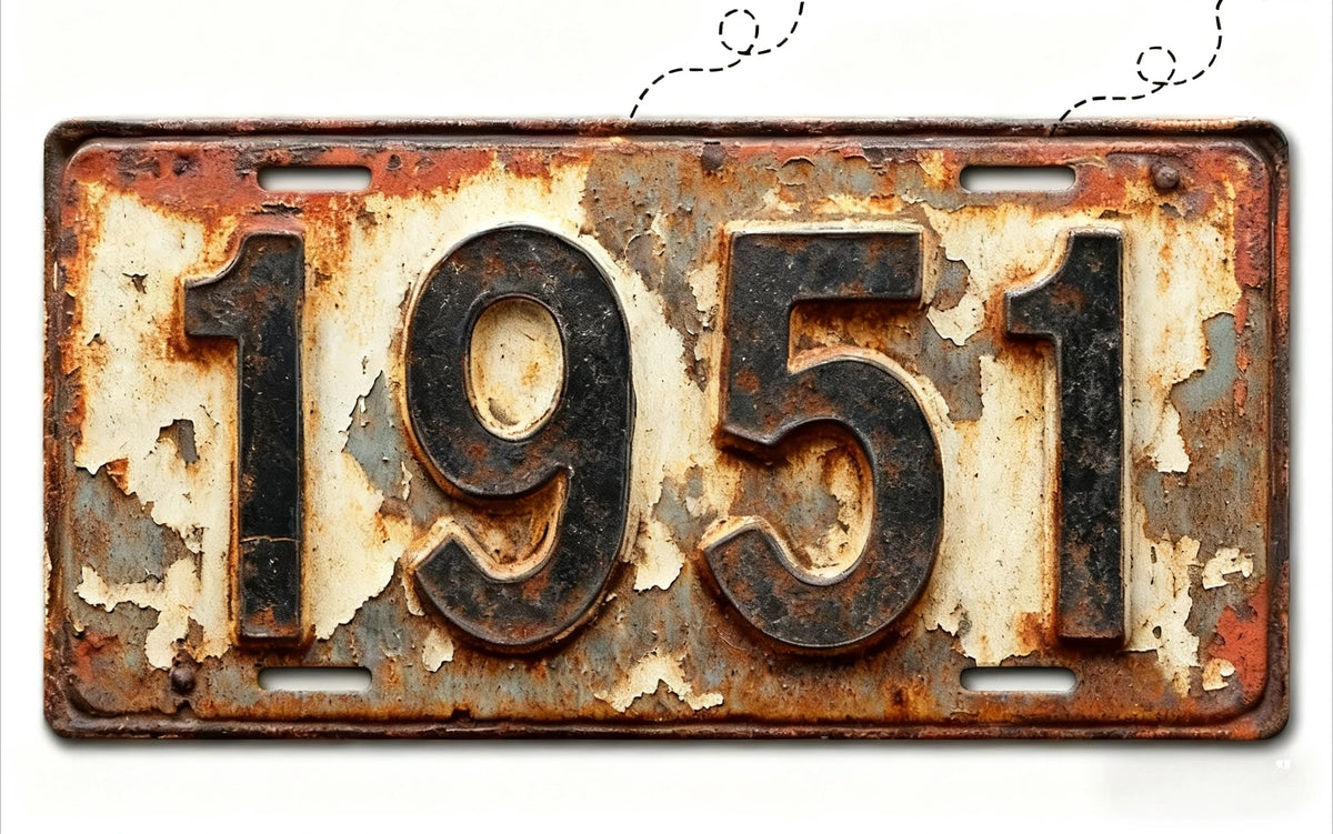 A vintage, weathered aluminum license plate with the year 1951 embossed on it.