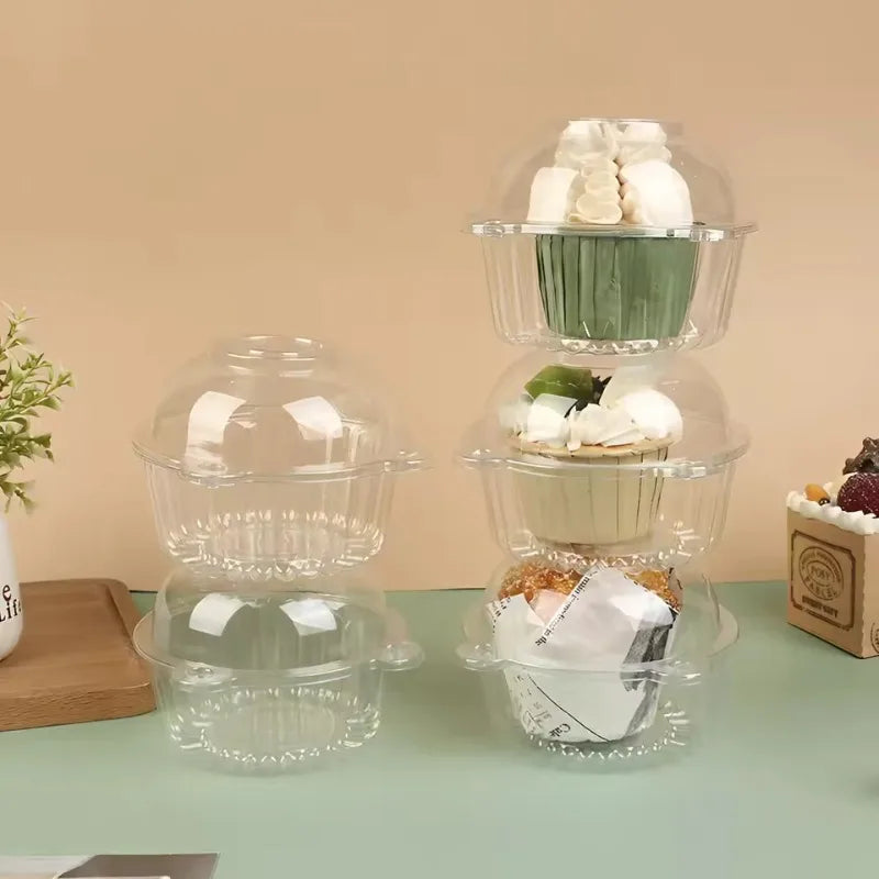 A clear plastic cake box with a lid is shown, containing small white and green decorative items.