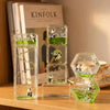A set of clear glass hourglass timers filled with green liquid and small panda figurines used as desk decor.