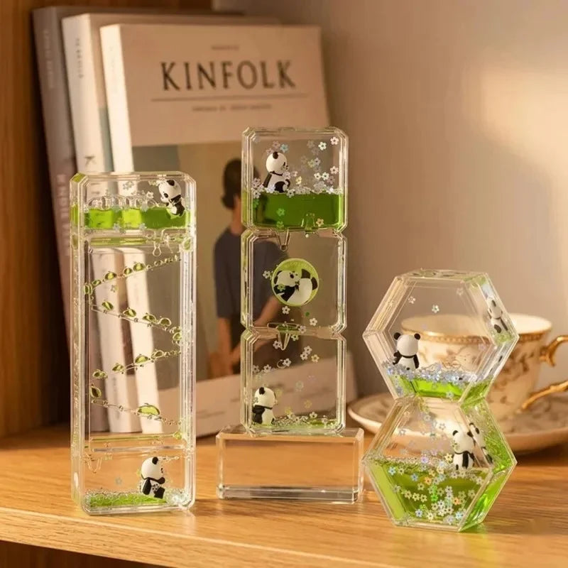 A set of clear glass hourglass timers filled with green liquid and small panda figurines used as desk decor.