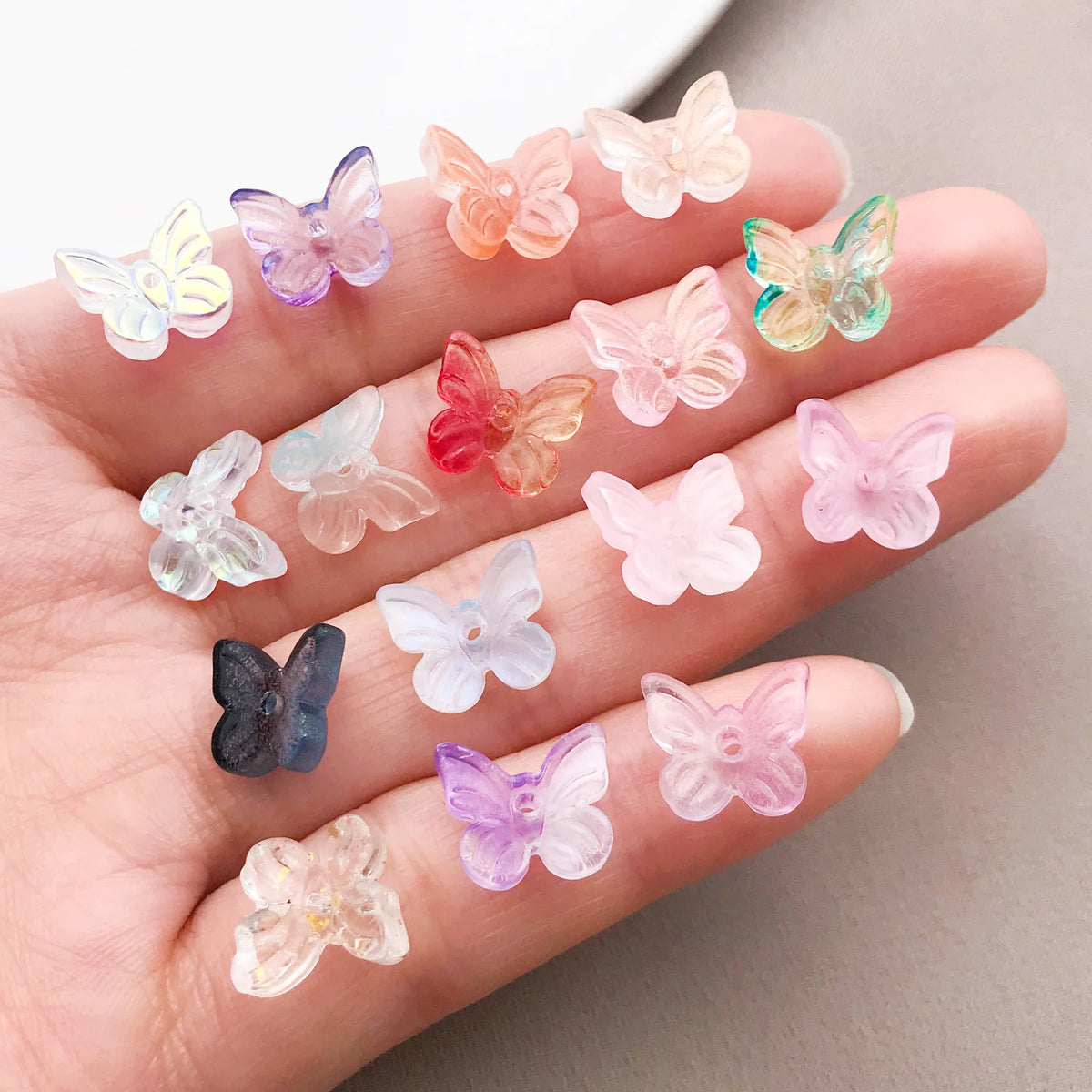 Variedad de cuentas de mariposa de vidrio coloridas dispuestas en una mano