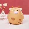 A cute cartoon cow figurine with pink nose and brown spots, labeled as a Bullish coin holder.