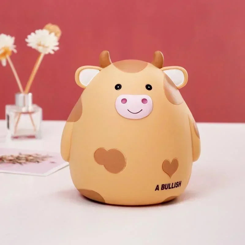 A cute cartoon cow figurine with pink nose and brown spots, labeled as a Bullish coin holder.