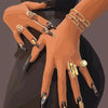 Nahaufnahme einer Frauens hand mit langen Nägeln, verziert mit gold- und blauem Nagelkunst, trägt ein goldenes Armband.