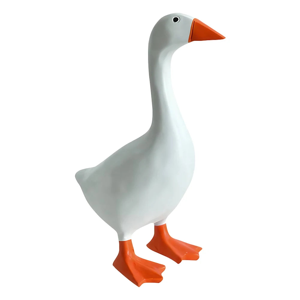 A white resin figurine of a goose with an orange beak and feet.