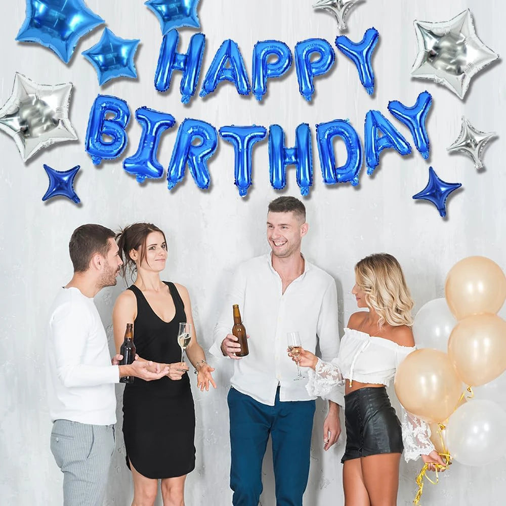 A couple celebrates a birthday with blue and silver foil balloons spelling out Happy Birthday against a white background.