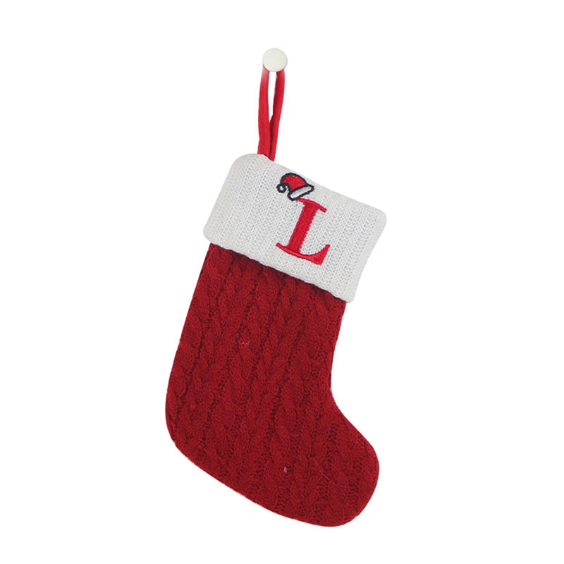 A red knitted sock with a white tag featuring the letter L and a red string for hanging.