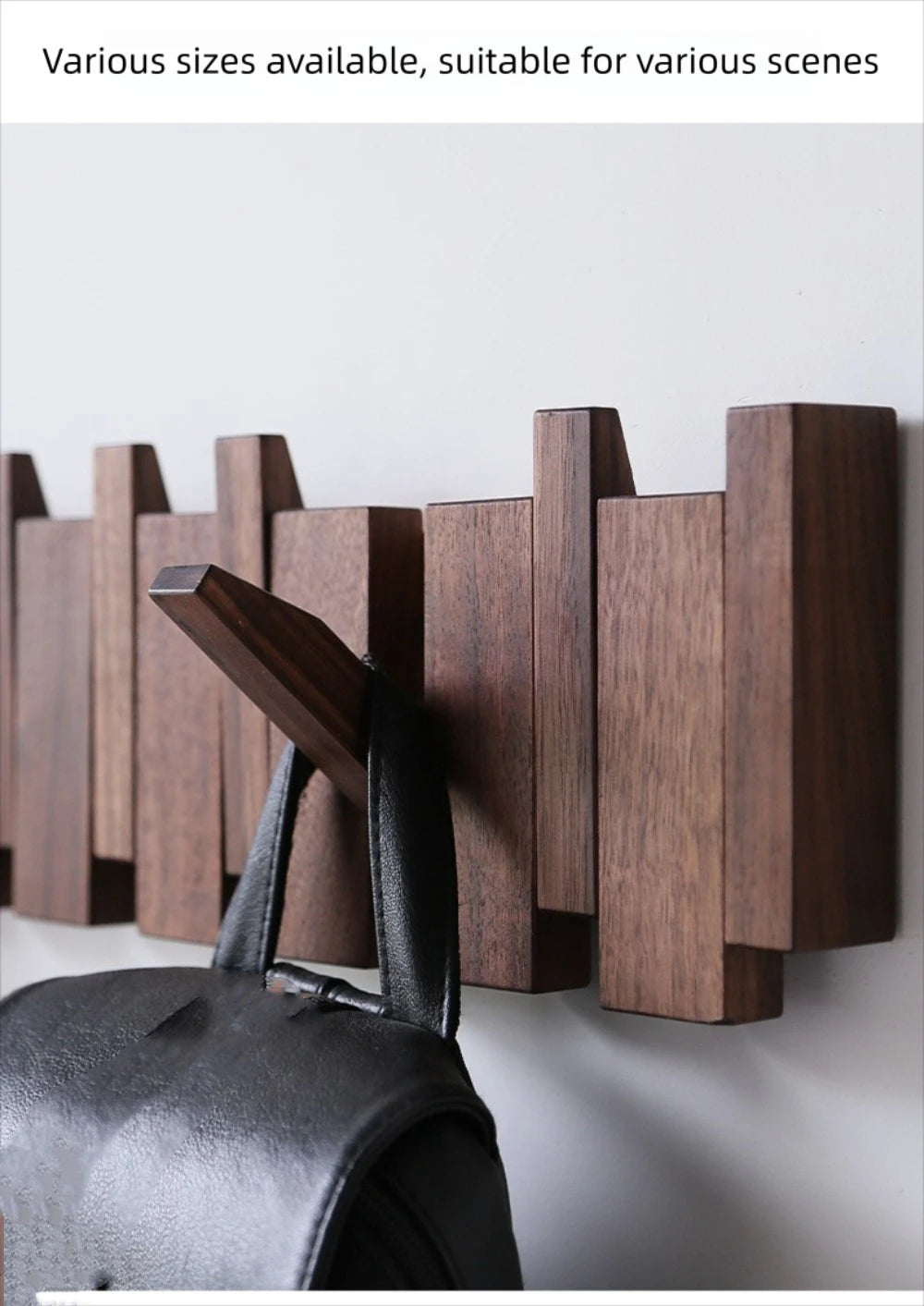 A dark wood piano key wall coat rack with eight vertical hooks mounted on a white wall.