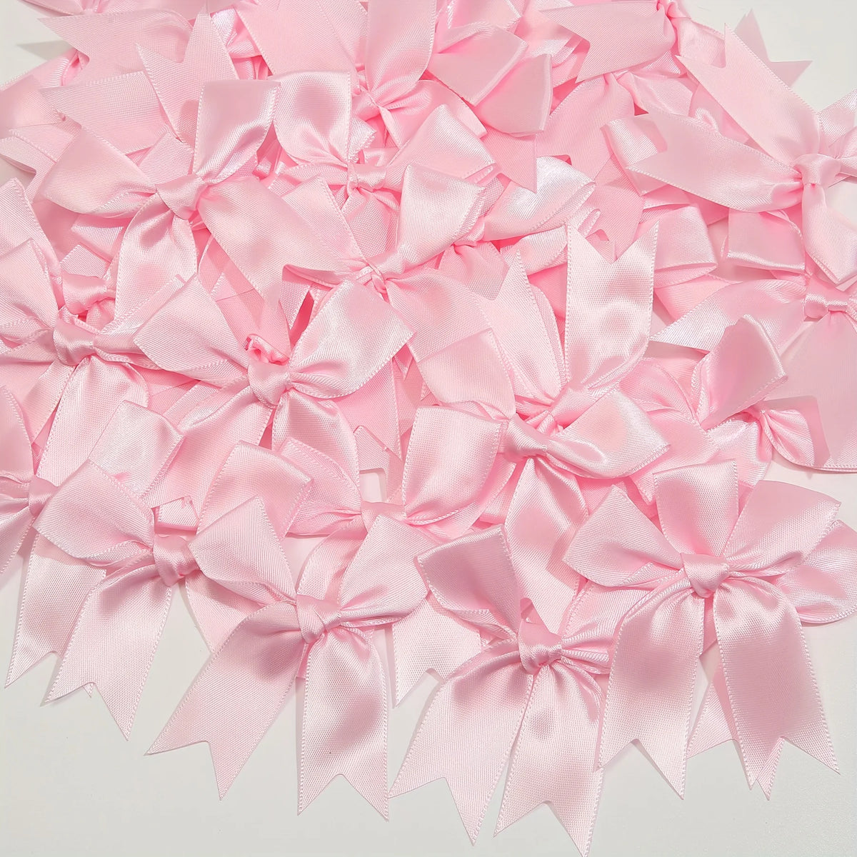 A pile of pink satin ribbon bows for gift wrapping and decor.
