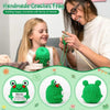 A woman is crocheting a green frog ornament with a young girl, showing the finished product.