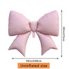 A pink bow-shaped foil balloon used for party decorations, shown flat.