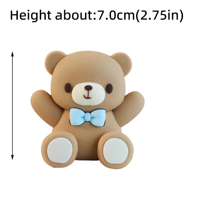 A light brown teddy bear baby block topper with a blue bow and white paws.