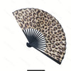 Leopard print folding hand fan with a black frame shown open and angled.