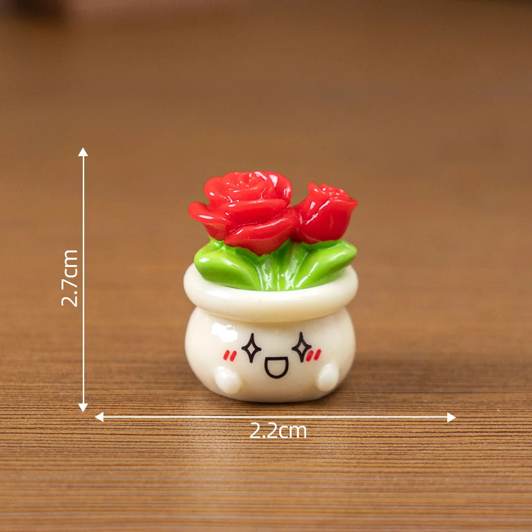A small white ceramic pot with green leaves and red rose resin charms for craft or dollhouse decoration.