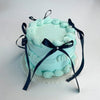 A light blue decorative fake cake with ruffled frosting and black ribbon accents.
