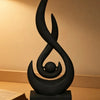 A black, stylized flame sculpture decor made from 3D printed material, displayed on a dark pedestal.