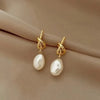 Elegant gold bean spliced pearl drop earrings displayed on a neutral fabric background.