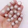 A hand holds a collection of 50 pearl and rhinestone flower crystals for DIY crafts.