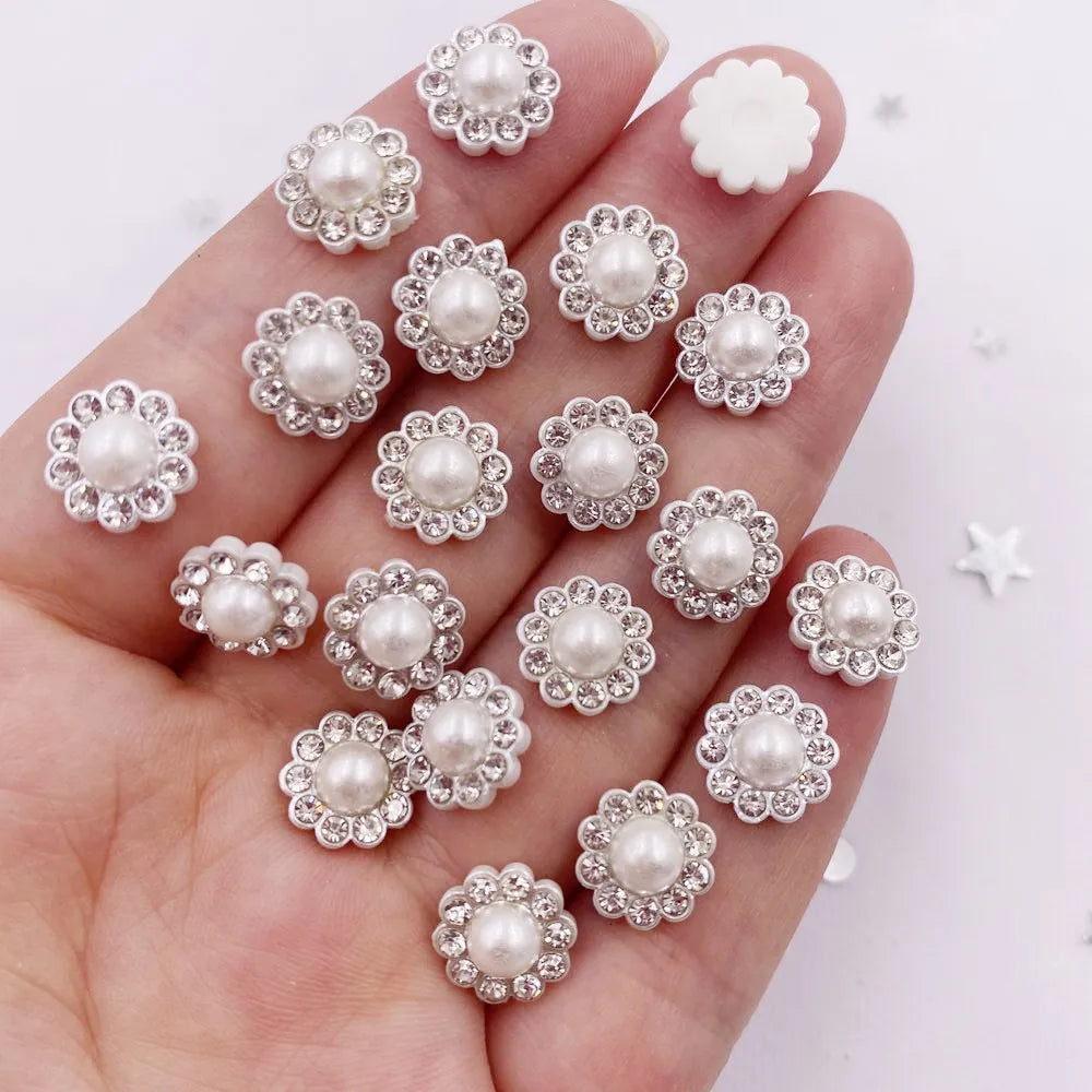 A hand holds a collection of 50 pearl and rhinestone flower crystals for DIY crafts.