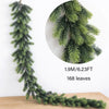 A long, green artificial pine garland with needles is displayed on a wooden surface.