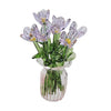 A bouquet of hand-blown glass purple and green flowers in a clear glass vase.
