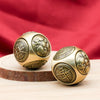 Two brass Chinese lucky coin spinners or fidget toys resting on a wooden surface with a red cloth background.